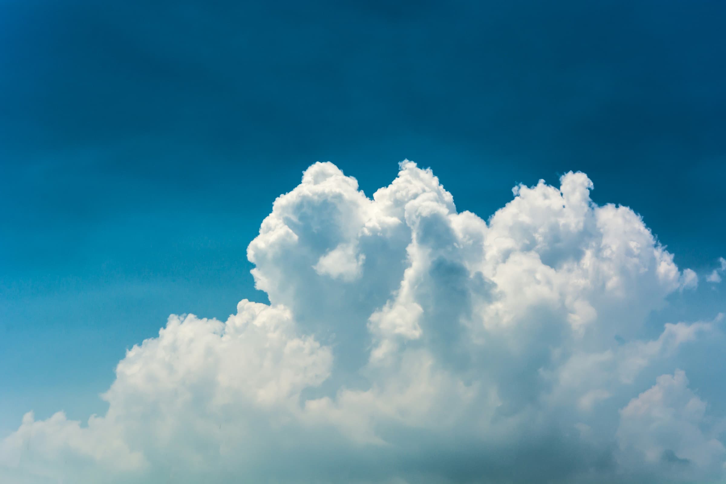 Sunlit cumulus cloud against a deep blue sky.